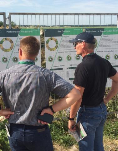 Photographie d'agriculteurs de dos devant des posters sscientifiques